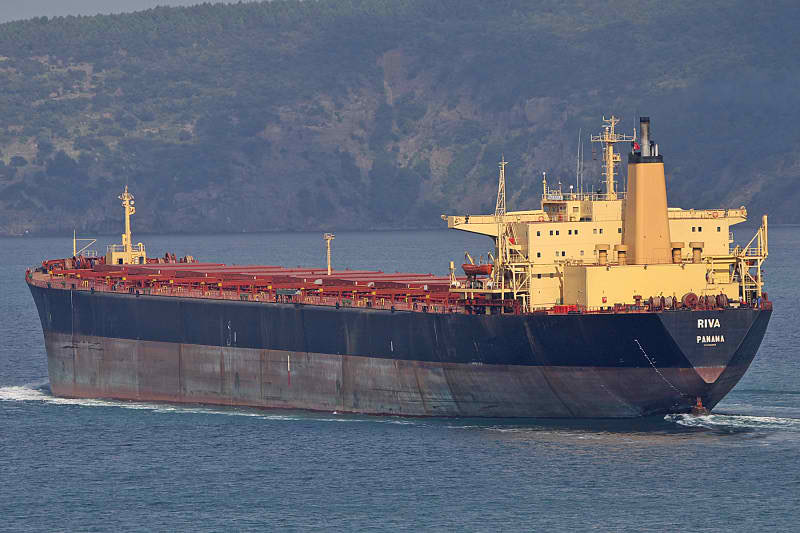 A large bulk carrier with a black hull and yellow superstructure underway at sea.